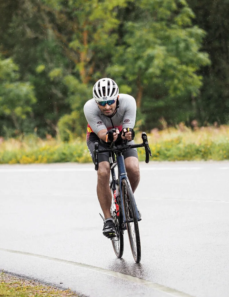 Akshit riding in aero position through heavy rain at Ironman 70.3